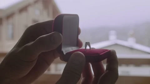 Hands are holding wedding ring in box for proposal. Man holds and opens red box Stock Footage 148205478