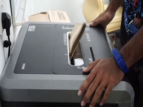 Hands are inserting office documents for disposal into shredder machines Stock Footage 86716708