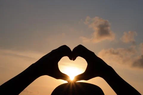 Hands are making a heart shape to let the sun pass through. Stock Photos