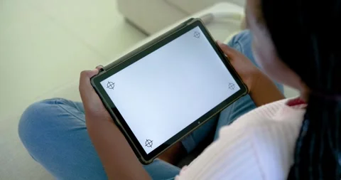 Hands are making small grip shifts, tilting tablet on couch lap for clearer Stock Footage 335625477