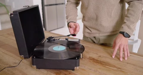 Hands are picking up black vinyl, placing on portable turntable on table, Stock Footage 342641776