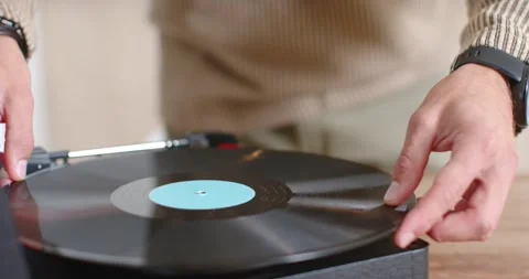 Hands are placing black vinyl with blue label on tabletop turntable lowering Stock-Footage 344405493