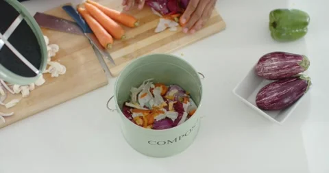 Hands are reaching for pale green compost lid, adding scraps and pressing for Video stock 344964517