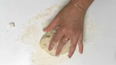 Hands are seen rolling out dough with a wooden rolling pin on a floured surface, Stock Footage 336066294