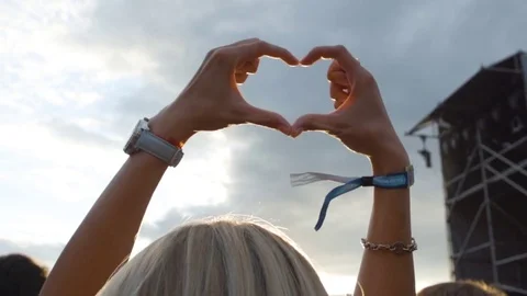 Hands are in the shape of heart at the sunset. Hands shaped at a music festival Stock Footage 80859488