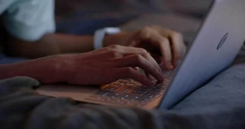 Hands are shifting from rest and typing on laptop on bed, wristwatch glowing for Stock Footage 339800758