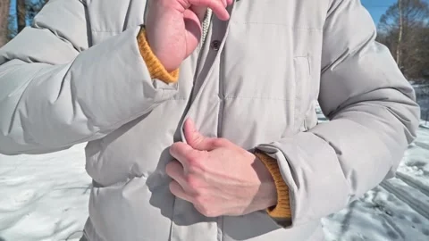 Hands are shown being rubbed together and tucked inside a jacket in snowy Vidéo 337101617