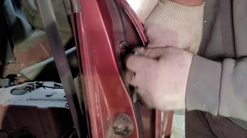 Hands are shown working on a car door lock in a garage. Tools are used carefully Stock Footage 332227067
