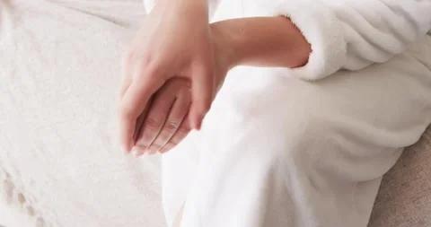Hands are squeezing white cream tube and dispensing lotion then massaging into Stock Footage 344333207
