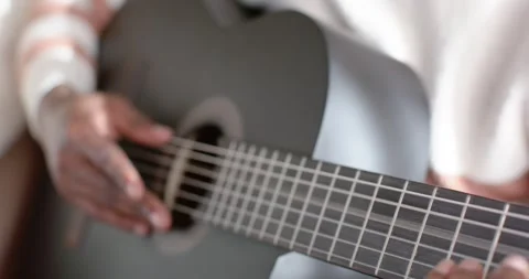 Hands are starting to pluck black guitar strings, forming chords and sliding on 库存影片 343888835