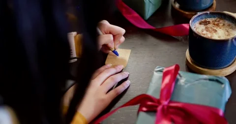 Hands are steadying gift tag on dark table writing label with blue pen for gift Stock Footage 345588404