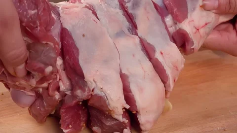 Hands are stuffing a raw meat leg with garlic Stock-Footage 293493738