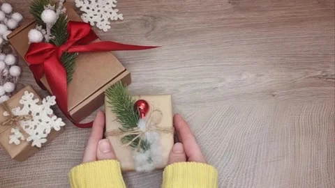 Hands are on the table wrapped Christmas gift, top view of the table with Stock Footage 294098301