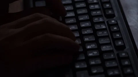 Hands are typing on a keyboard in a dark room. Stock Footage 119200710