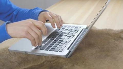 Hands are typing message on laptop keyboard standing on rug on a wooden table Stock Footage 100269975