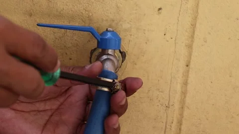 Hands are using screwdriver to loosen clamp for remove blue rubber hose Stock Footage 147583167