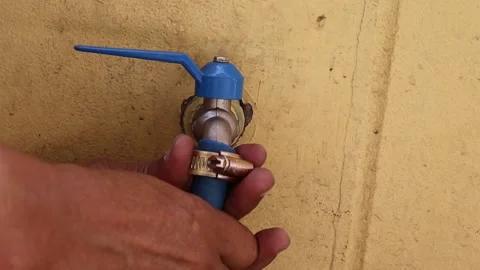 Hands are using screwdriver to tighten the clamp to blue rubber hose Stock Footage 147583191