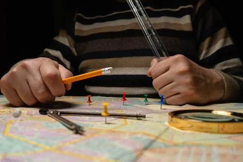 Hands are working with a map on a table. Colorful pins are placed in differ.. 库存照片