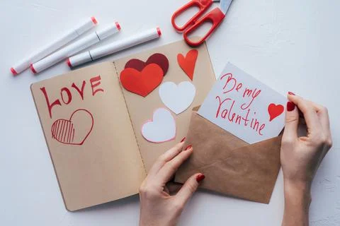 Hands are wrapping a valentine in an envelope. Craft cards and gifts. Foto stock