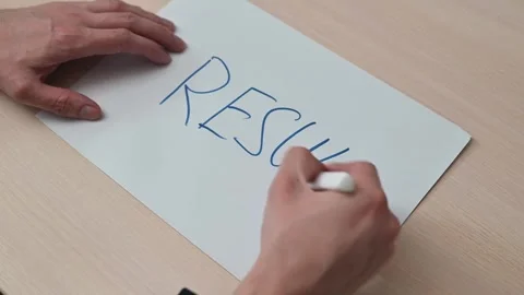 Hands are writing the word RESULT in capital letters on a sheet of paper with a Stockbeeldmateriaal 337550419