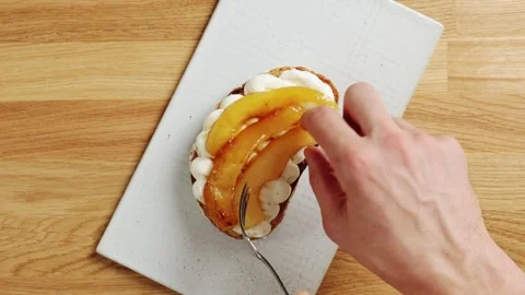 Hands arrange caramelized pear pieces on ricotta toast with fork. Video stock 344769711