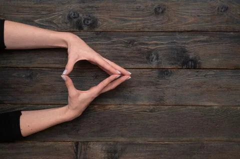 Hands arranged in triangular shape, with fingers touching lightly. rustic w.. Stock Photos