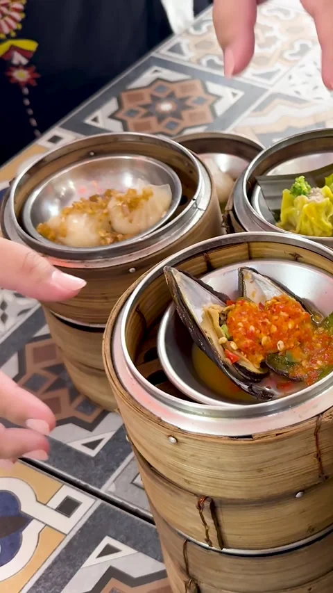 Hands Arranging Bamboo Dim Sum Steamers on Patterned Table Stock Footage 327346653