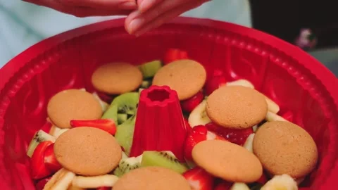 Hands arranging biscuits on a fruit dessert in a kitchen Stock Footage 342874534