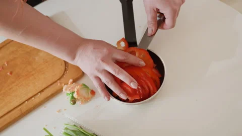 Hands arranging concentric tomato slices in small frying pan on white countertop 库存影片 343676842