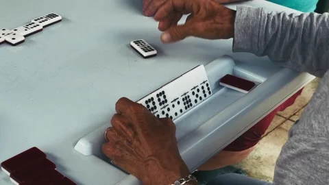 Hands arranging domino tiles during a tabletop game in outdoor setting Stock Footage 322513383