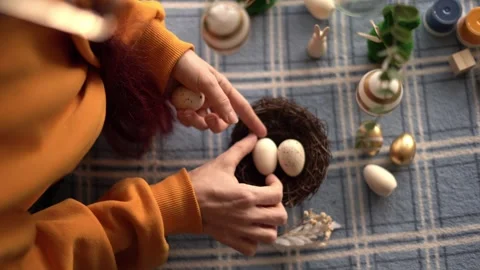 Hands arranging Easter eggs in nest with spring craft decor Stock Footage 329118722