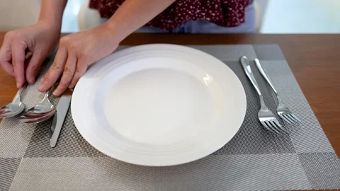 Hands Arranging Silverware and White Ceramic Plate on Wooden Dining Table 스톡 동영상 334984893