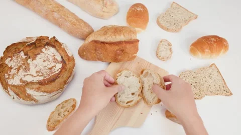 Hands Arranging Sliced Artisan Bread on Wooden Board Top View Stockbeeldmateriaal 337521259