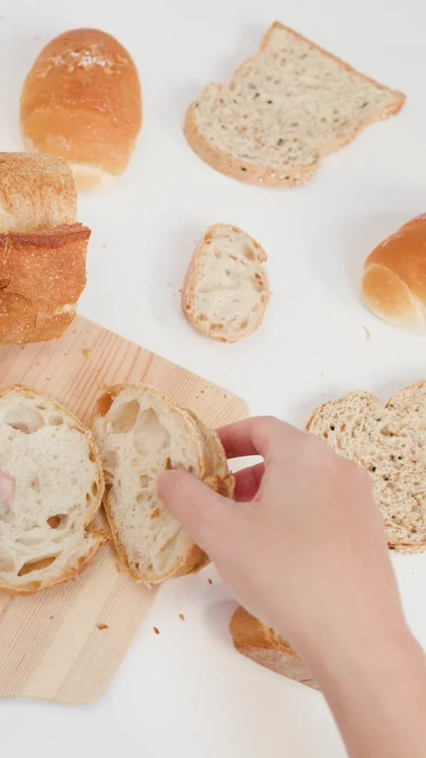 Hands Arranging Sliced Artisan Bread on Wooden Cutting Board Stock Footage 337767611
