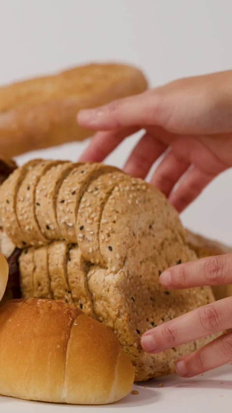 Hands Arranging Sliced Whole Wheat Bread and Assorted Pastries Stock Footage 337691151