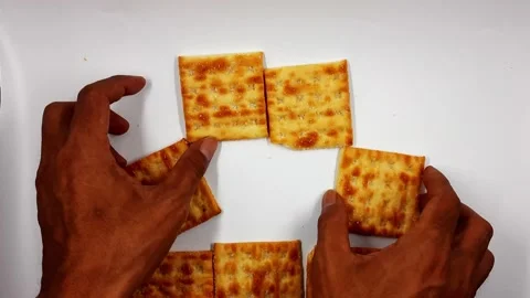 Hands arranging square crackers into a circular pattern video Stock Footage 331004506
