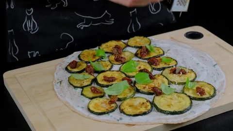 Hands arranging zucchini and basil on pizza in Cooking Stock Footage 341424794