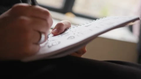Hands of artist drawing with pen in notebook indoors, close-up shot Stock Footage 268604276