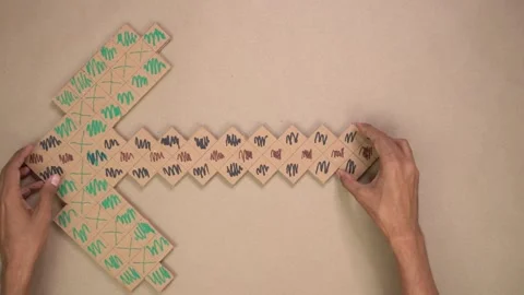 Hands assembling cardboard pixel pickaxe craft Stock Footage 327695229