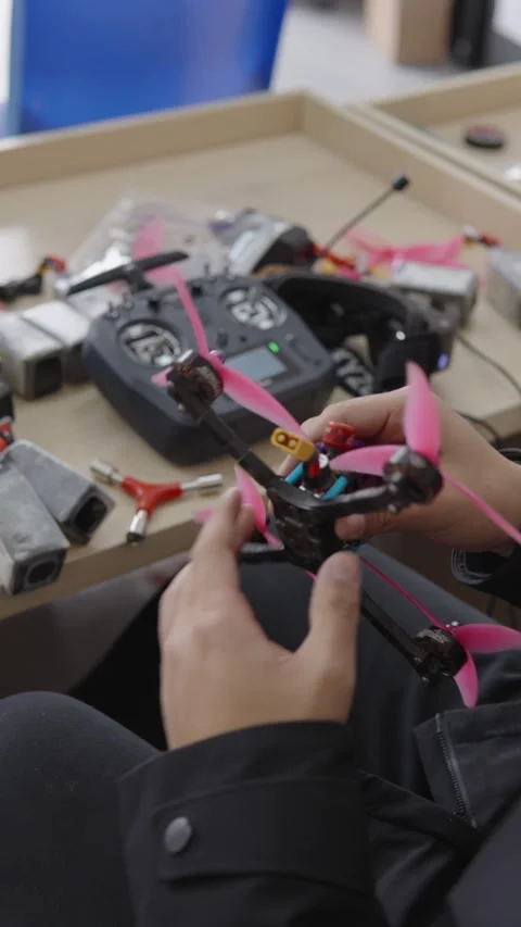 Hands assembling civilian drone in workshop, consumer technology repurposed for Stock Footage 328986791