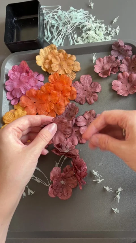 Hands assembling a colorful handmade flower wreath on a gray craft table Stock Footage 345718597