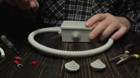 Hands assembling electrical components with a flexible conduit and connectors on Stock Footage 327655088