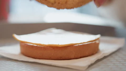Hands assembling filled sponge cake with glossy glaze, golden edges and soft Stock Footage 343544898