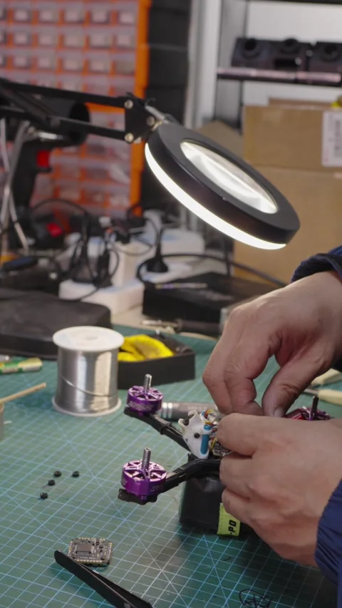 Hands assembling FPV drone at under magnifying lamp, representing modern drone 스톡 동영상 328986572