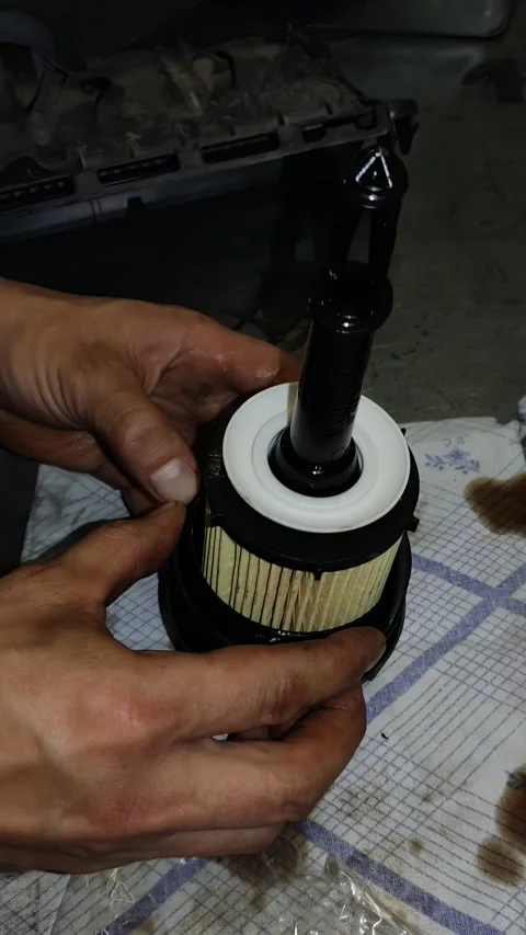 Hands assembling a new paper oil filter element onto a plastic cap. Stock Footage 343416536
