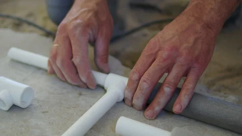 Hands assembling plastic pipe joints on concrete floor Stock Footage 312474532