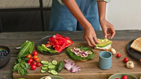 Hands assembling a sandwich from full grain bread with avocado and vegetables Stock Footage 160850571