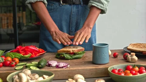 Hands assembling a sandwich from full grain bread with avocado and vegetables Stock Footage 160850620