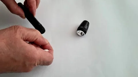 Hands Assembling Small Black Flashlight on White Surface for Maintenance Demo 動画素材 332890566
