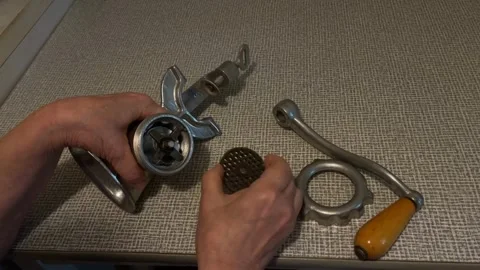 Hands assembling vintage meat grinder on textured metal table surface backg.. Stock Footage 344422200